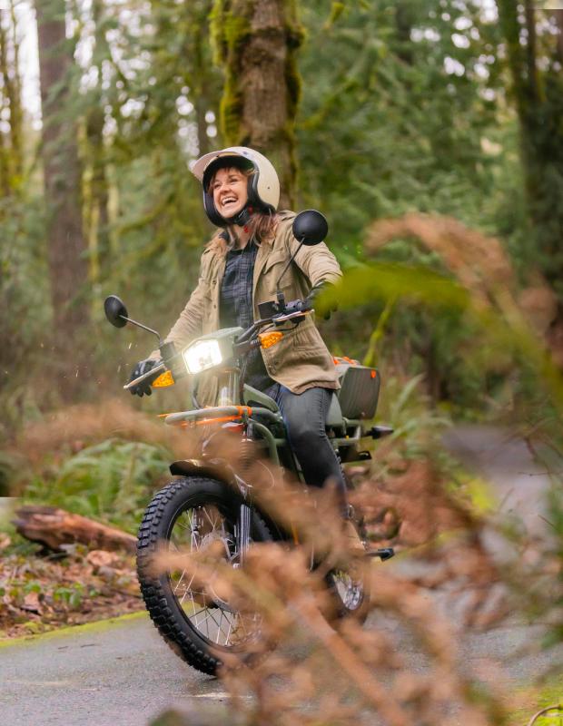 Femme pilotant un UBCO sur une route en foret