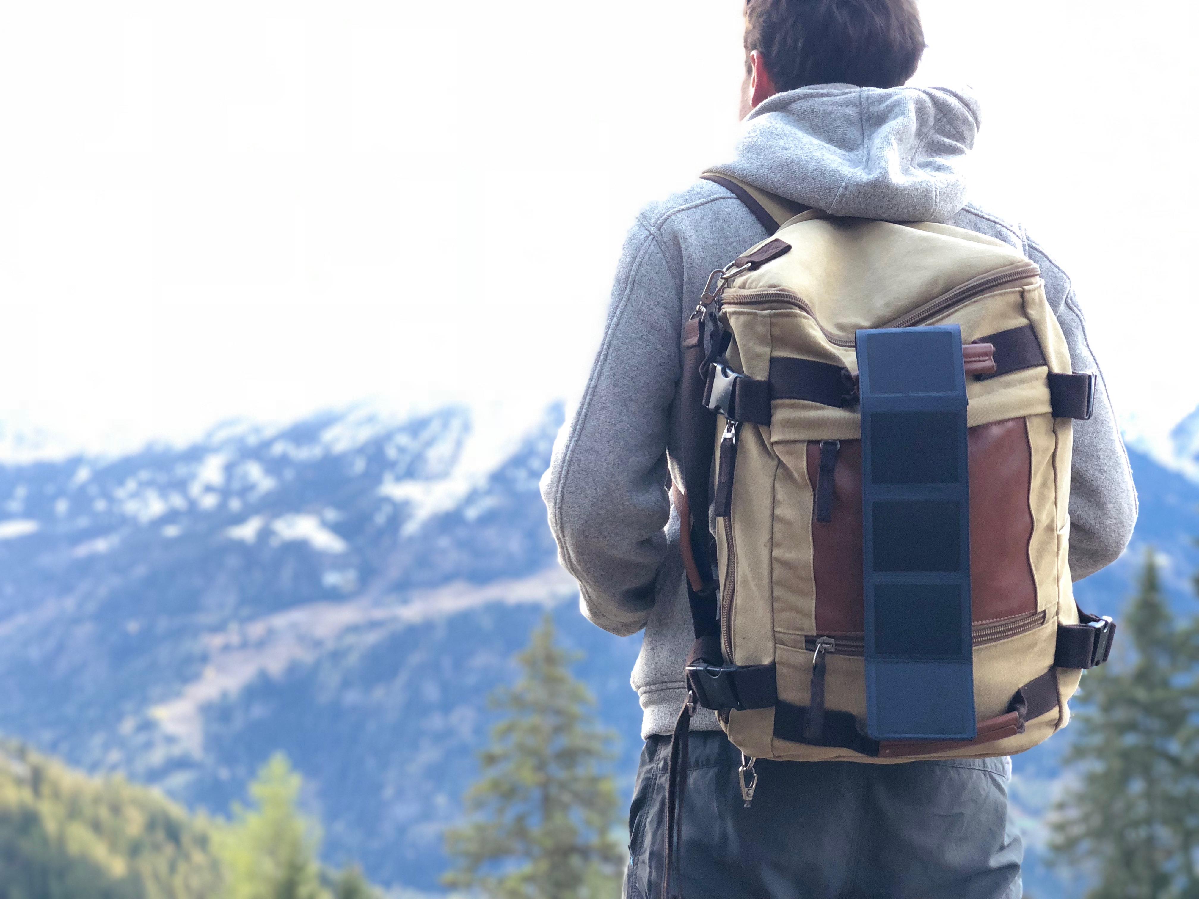 Homme se trouvant dans un paysage montagneux avec ses panneaux solaire de poche SUNSLICE